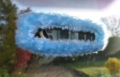 Handmade baby blue faux fur rear-view car mirror cover with a soft, fluffy texture, shown installed in a vehicle.